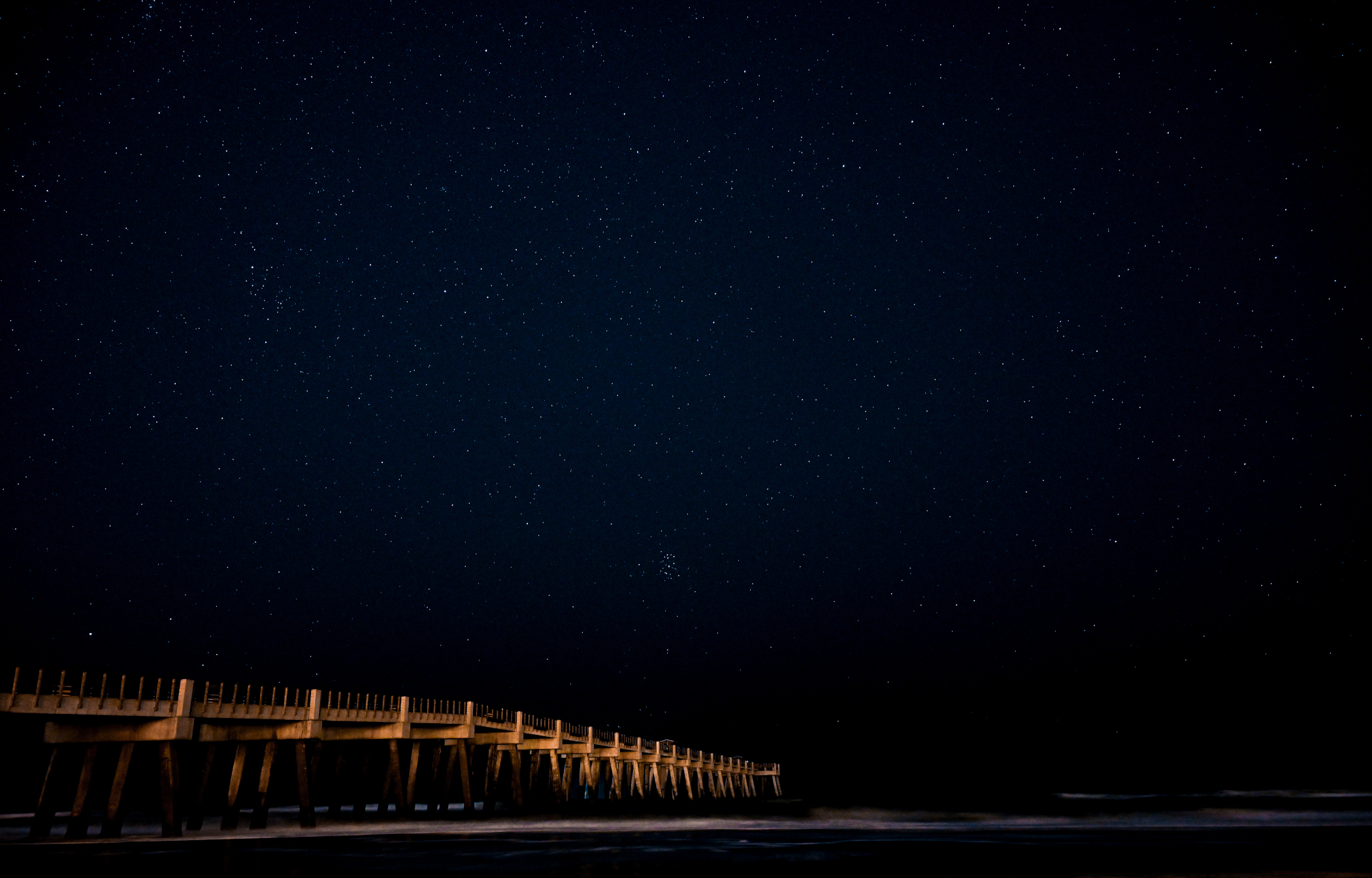 The Jacksonville Beach pier under an inky blue night sky filled with stars.